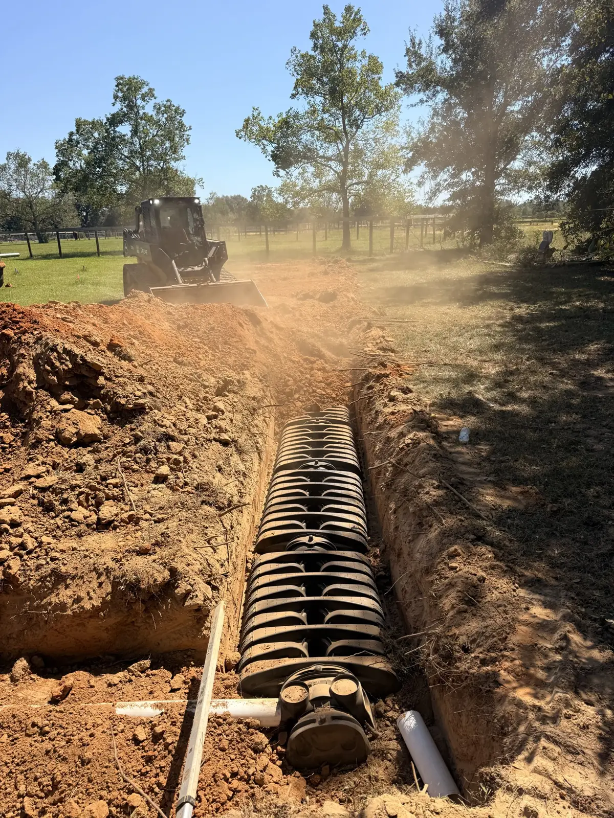 Drain field chamber trench with equipment in the background