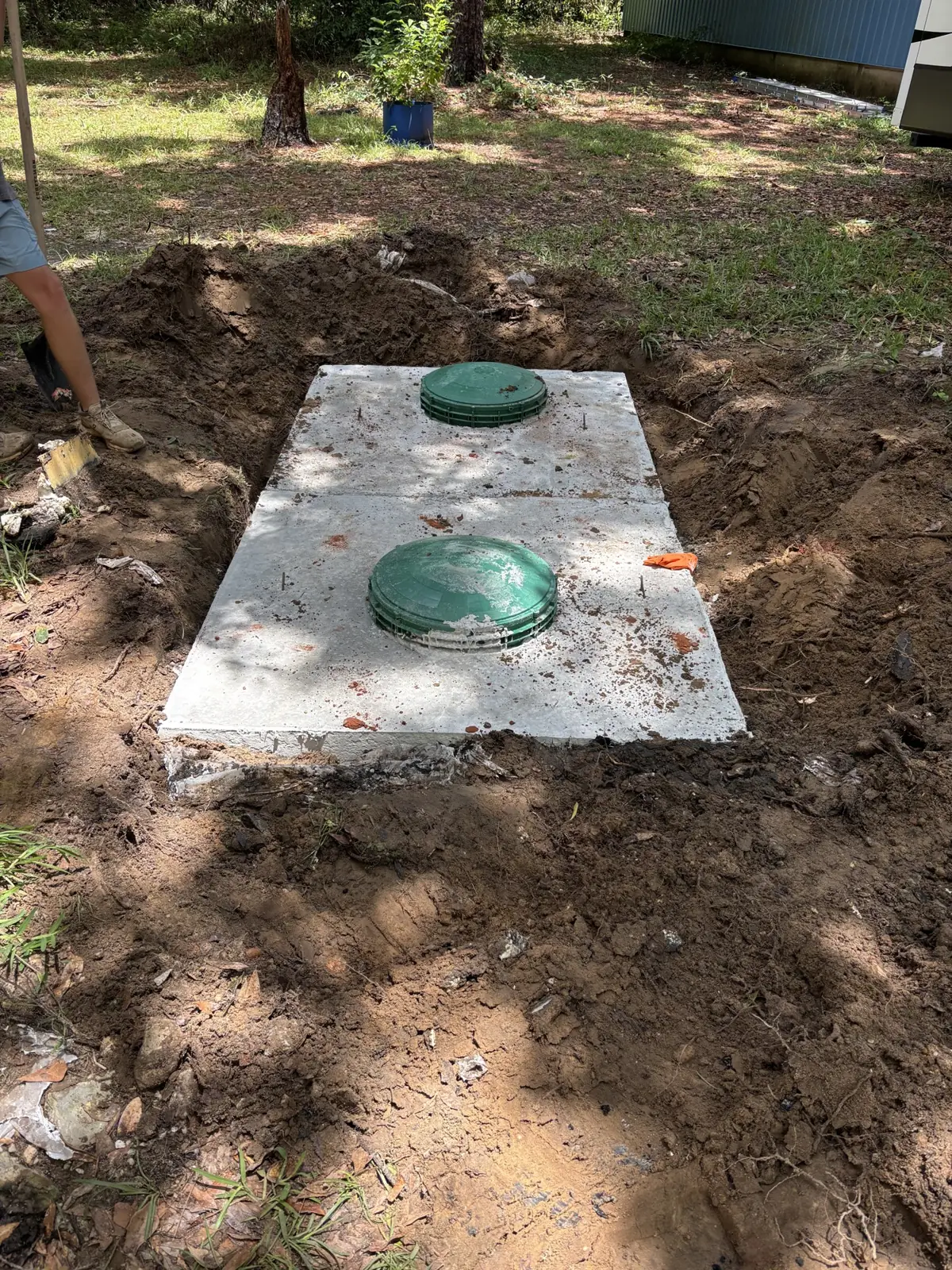 Concrete septic tank with green risers set in the ground