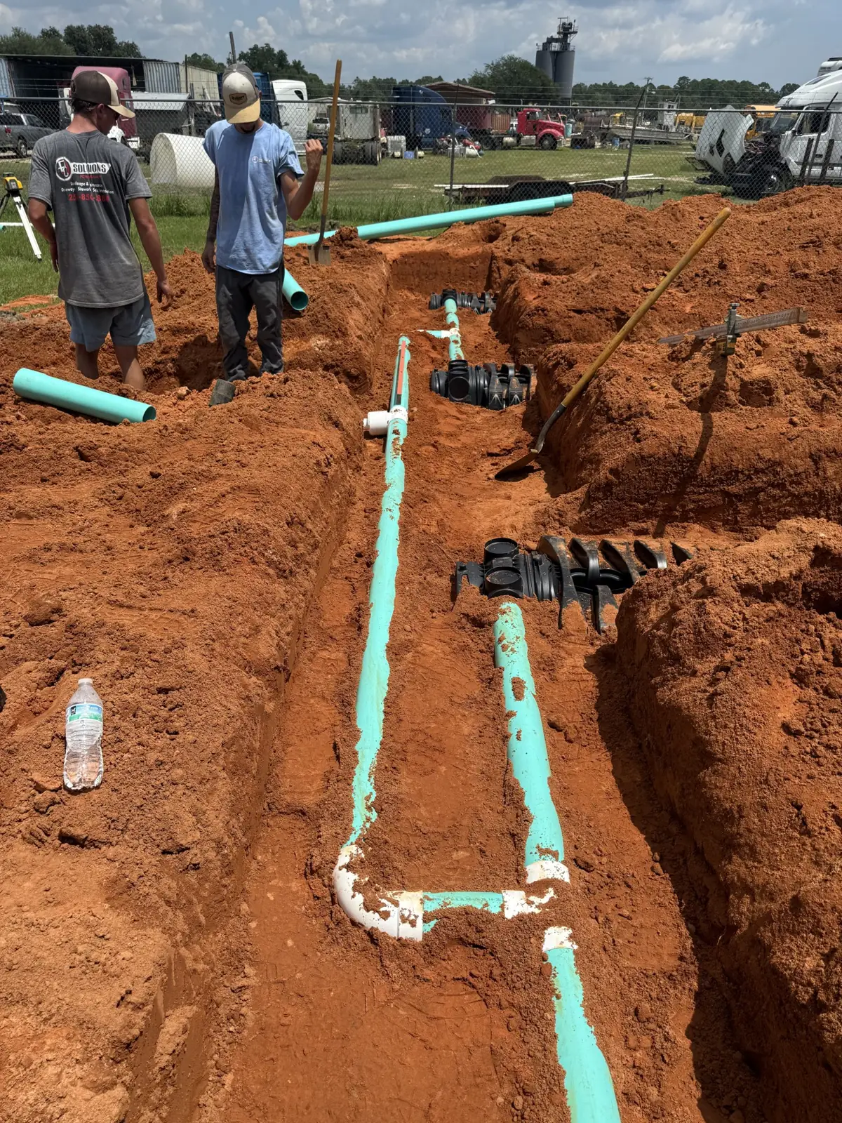 Crew members and teal pipe in an open trench