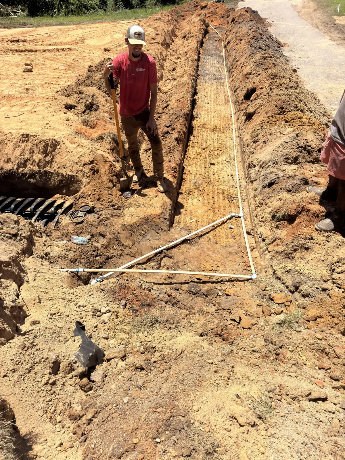 Technician standing in a staked drain-field trench