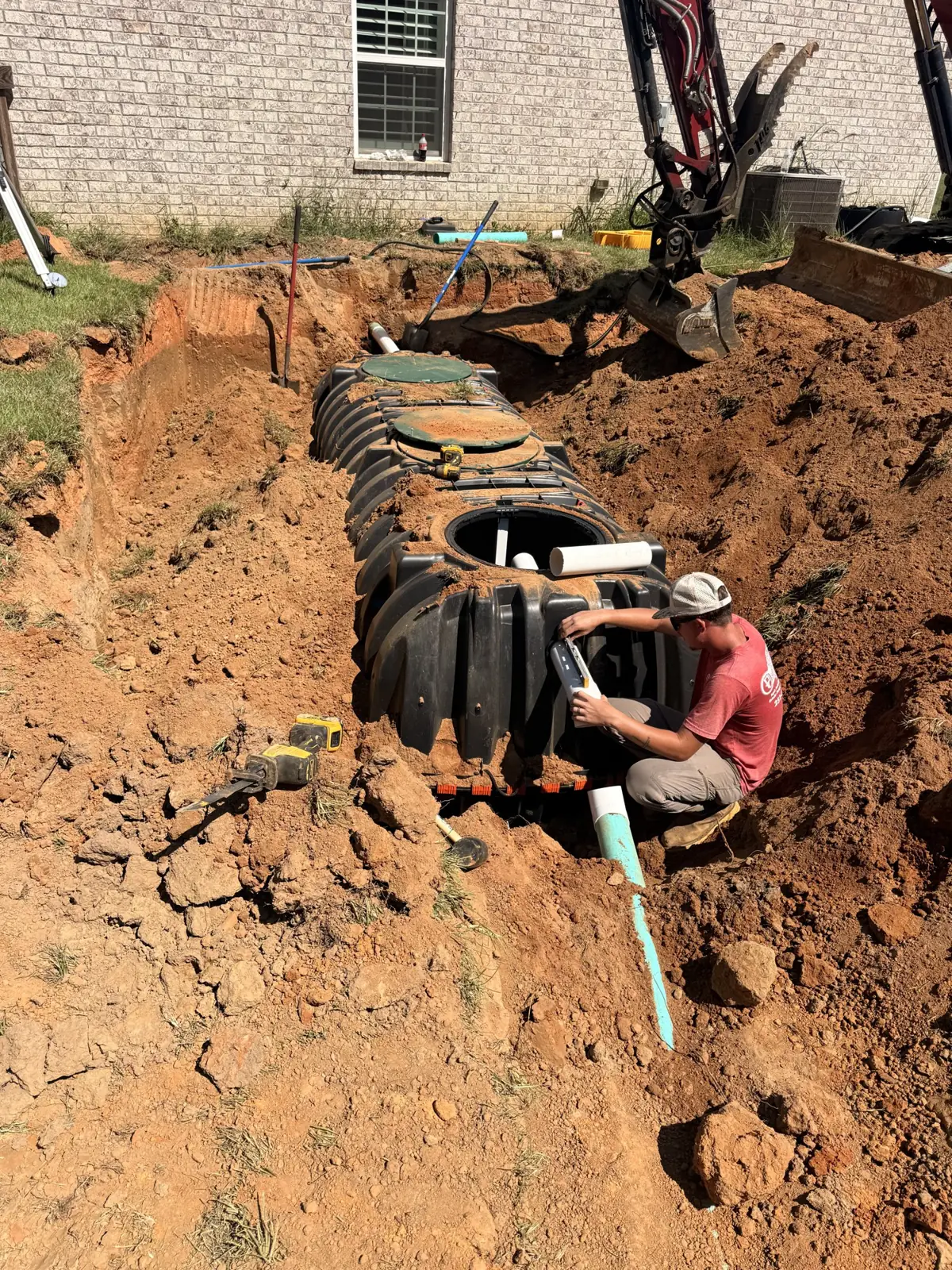 Technician working on a septic tank installation beside a home
