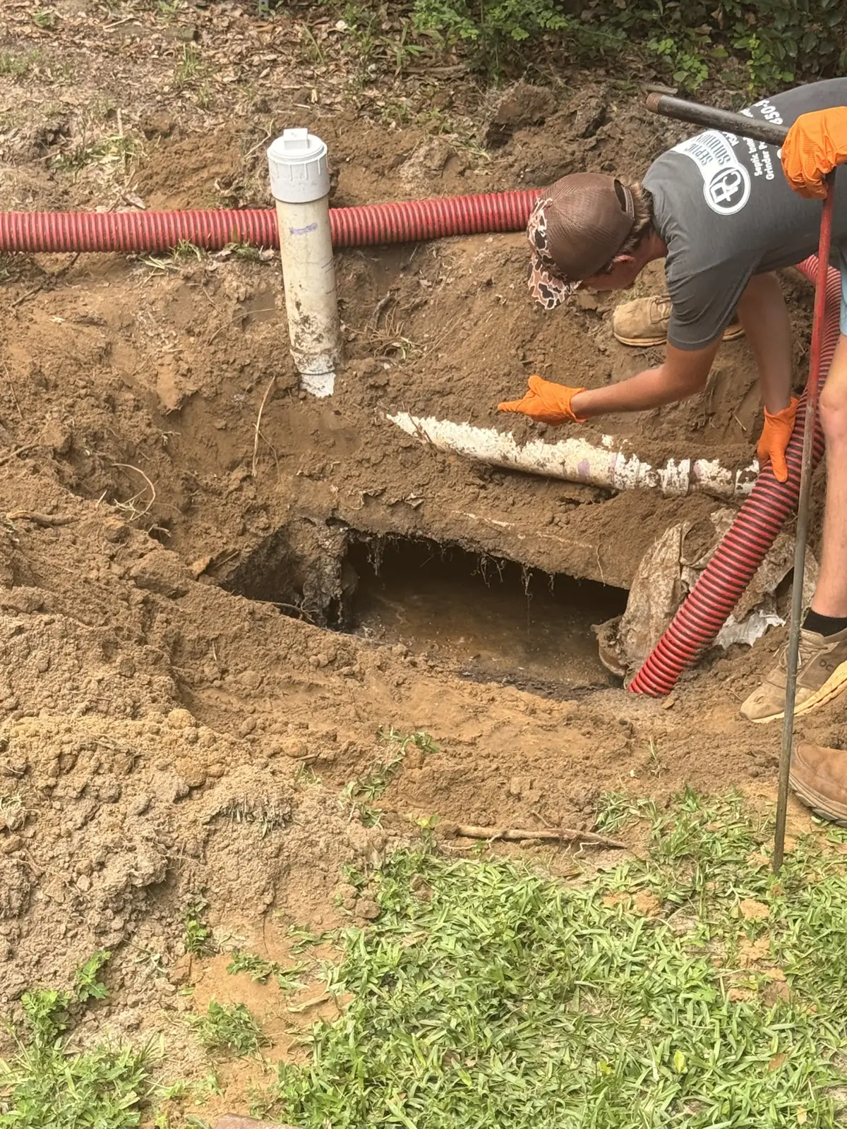 Technician working on piping in an open septic trench