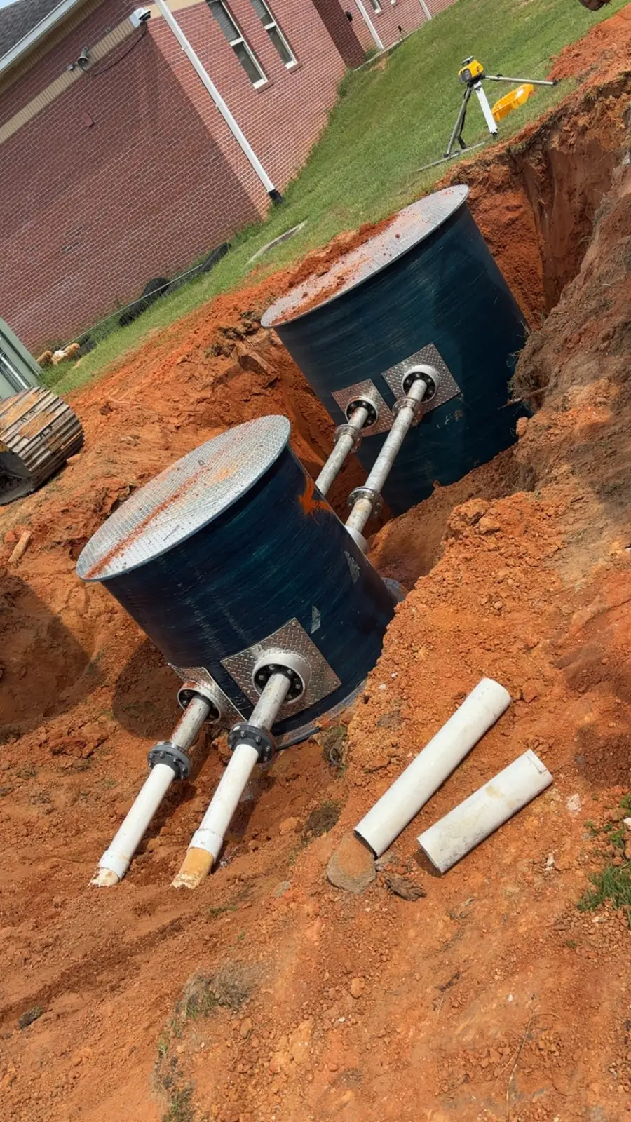 Two dark tanks with riser pipes set in an excavation